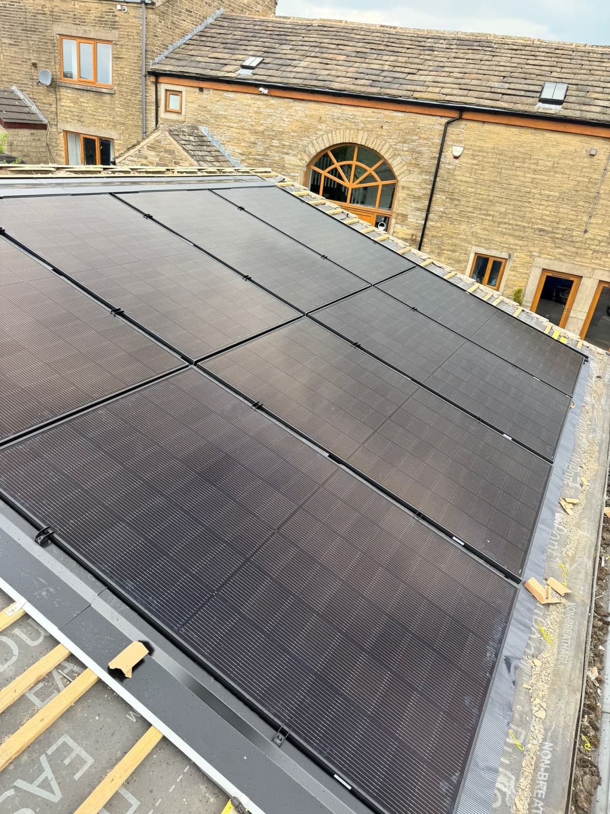 All-black solar PV panels installed on the pitched slate roof of a stone barn conversion