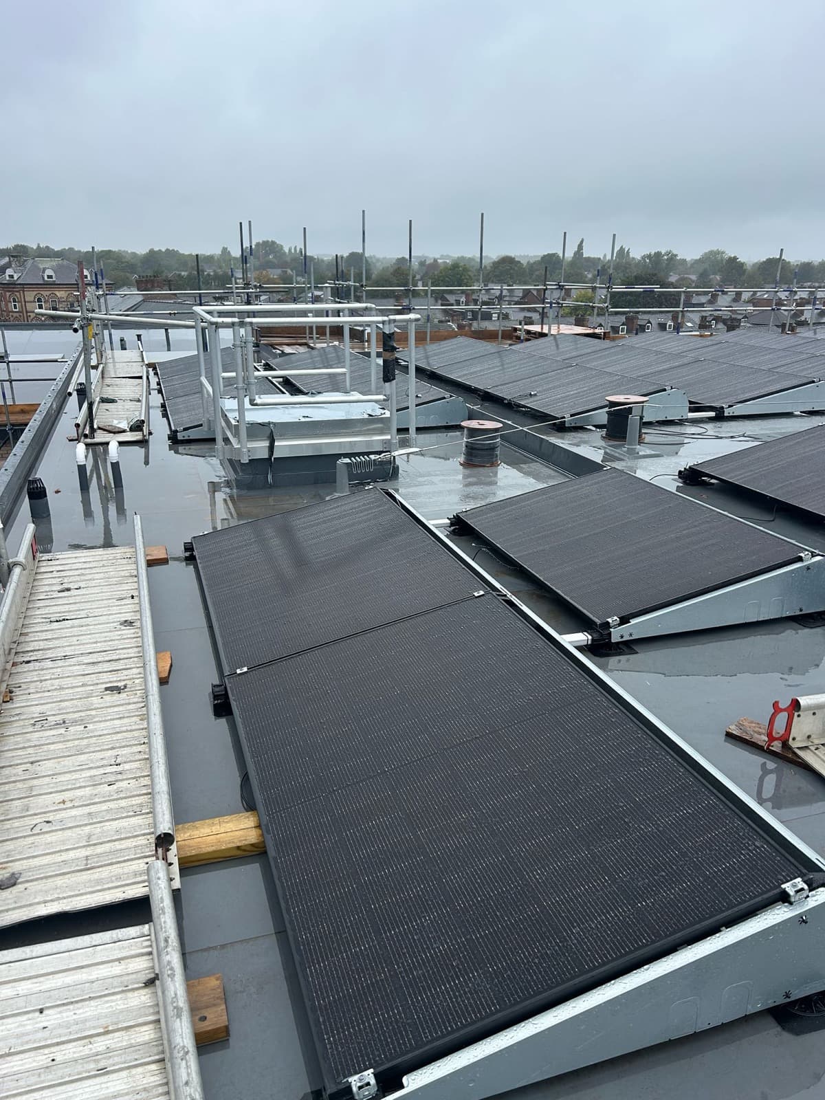 Commercial rooftop solar array on ballasted tilt frames on a flat-roofed building